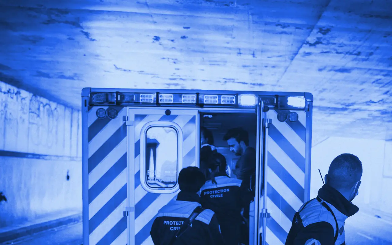 Responders in uniform at the back of an ambulance, seen from behind